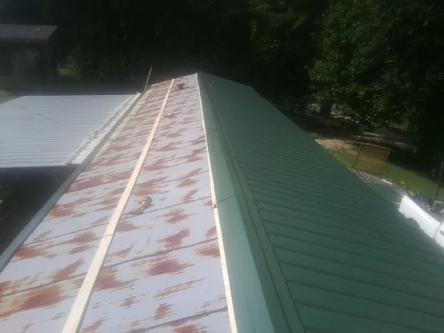 Old rusted panels beside newly installed green metal roofing — Wind Damage Roof Repair by Roofing Brothers in Hildale