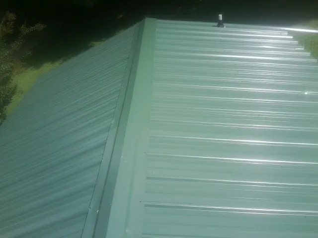 New green metal panels meeting at the ridge of a roof — Flat Roof Repair work by our crew in Hildale
