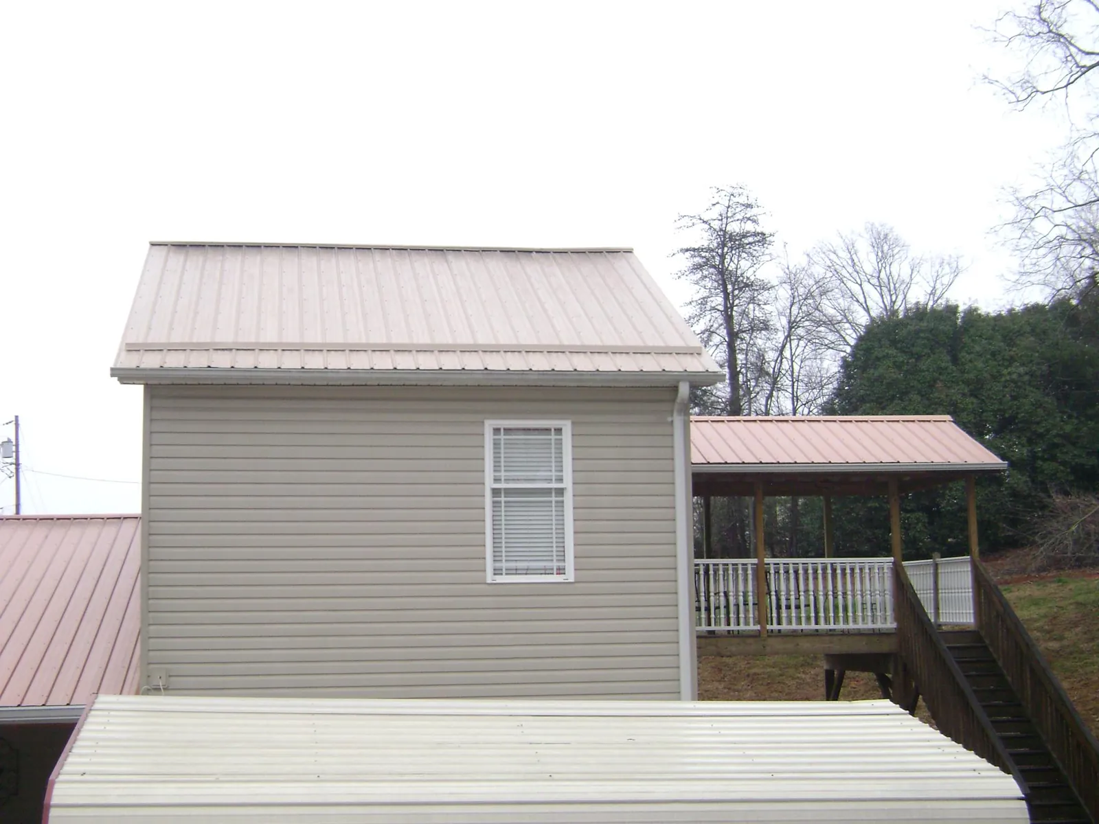 Tan metal roofs on a two story addition and attached porch, from a Roof Replacement job in Hildale