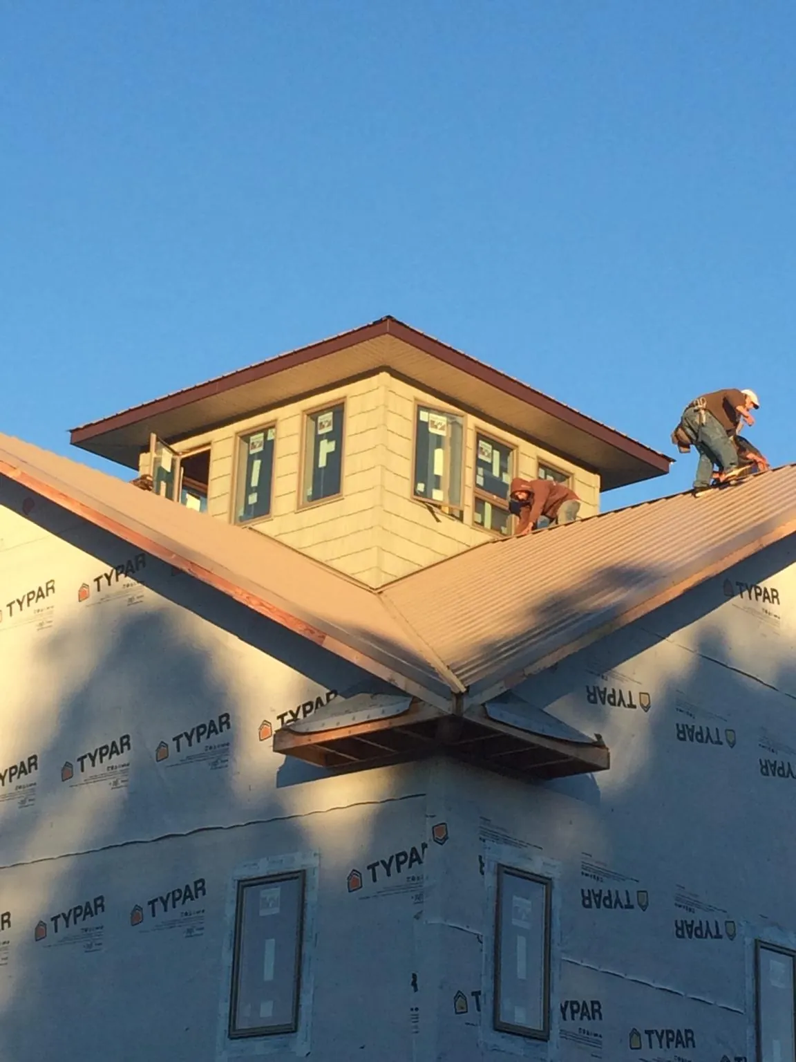 Roofers working around a rooftop cupola on a new metal roof at sunset — Roof Waterproofing in Hildale by Roofing Brothers